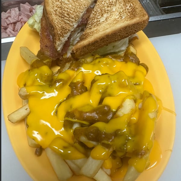 A diner-style plate with chili cheese fries and a toasted sandwich cut in half.