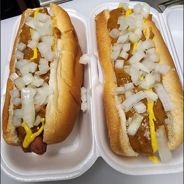Two St Clair Coney Island hot dogs with chili, mustard, and diced onions in a styrofoam container.
