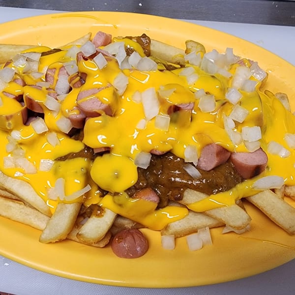St Clair Coney Island's chili cheese fries with chopped hot dogs and diced onions on a yellow plate.